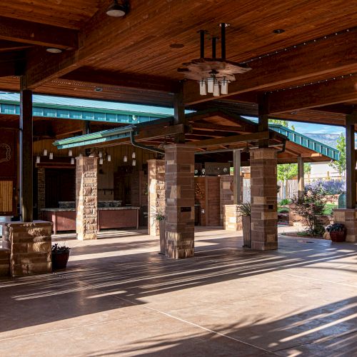 This image shows an open-air pavilion with wooden ceilings, stone columns, and decorative elements, illuminated by natural sunlight.