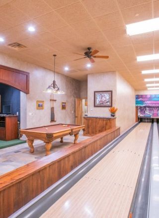 The image shows a home recreation area with bowling lanes and a pool table under warm lighting.